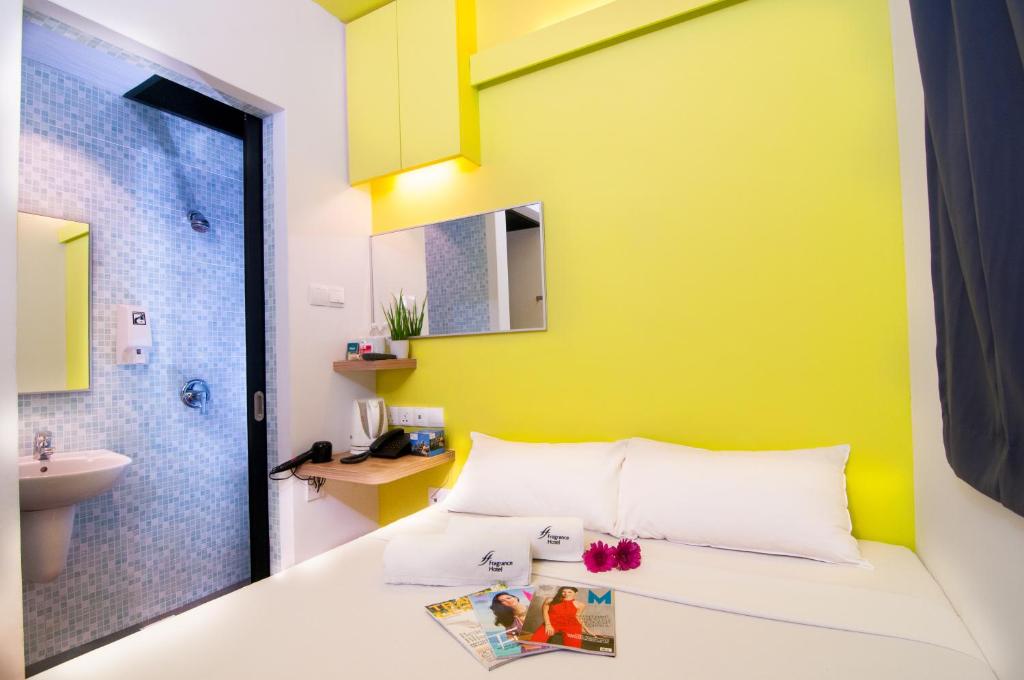 a bathroom with a bed with a yellow wall at Fragrance Hotel - Classic in Singapore