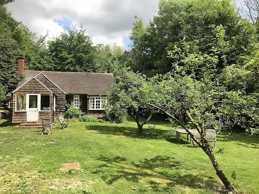 una piccola casa in un giardino con un albero di 3 Bed Cabin in the Woods a Barham