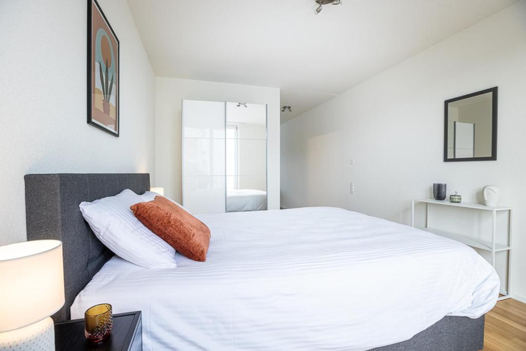 a bedroom with a large bed with white sheets at Nidfeld by Coliving in Lucerne