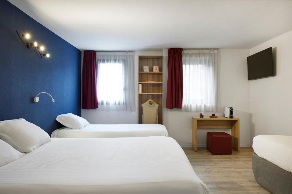 two beds in a room with blue walls at Hotel-Restaurant Isidore Nice Ouest in Nice