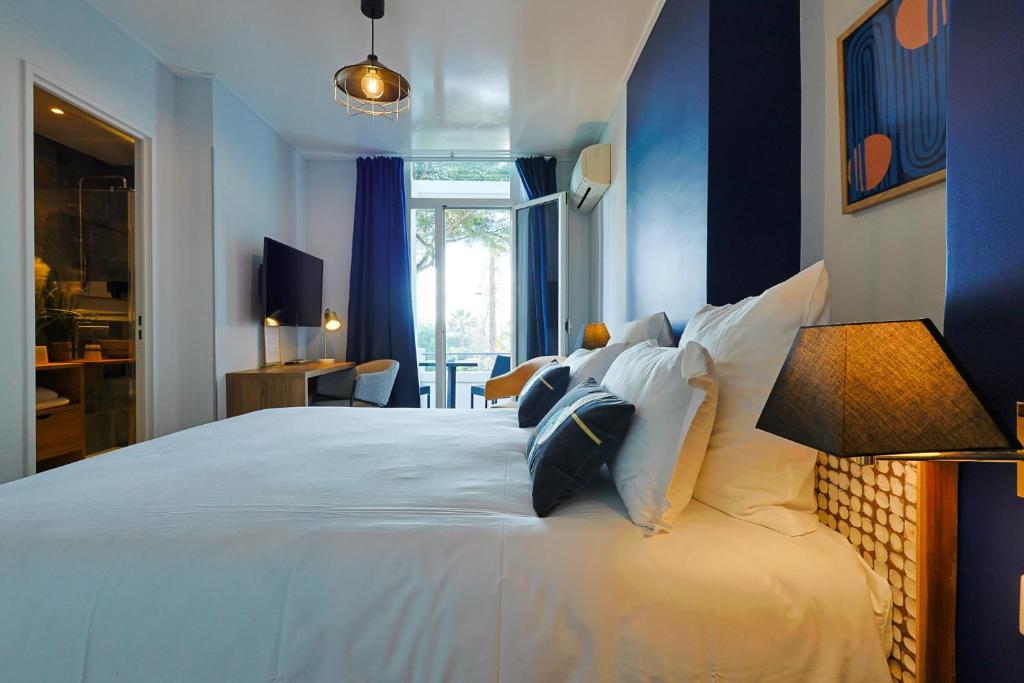 een slaapkamer met een groot wit bed met kussens bij Hotel Albert 1er in Cannes