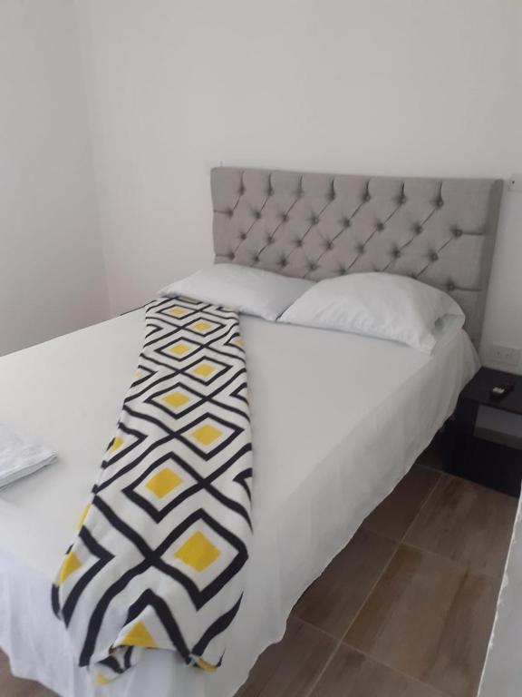 un letto bianco con una coperta nera e gialla sopra di caribepremiumvalledupar a Valledupar