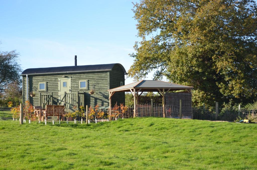 una casa con cenador frente a un campo en Spring Grounds Farm Shepherd Huts 