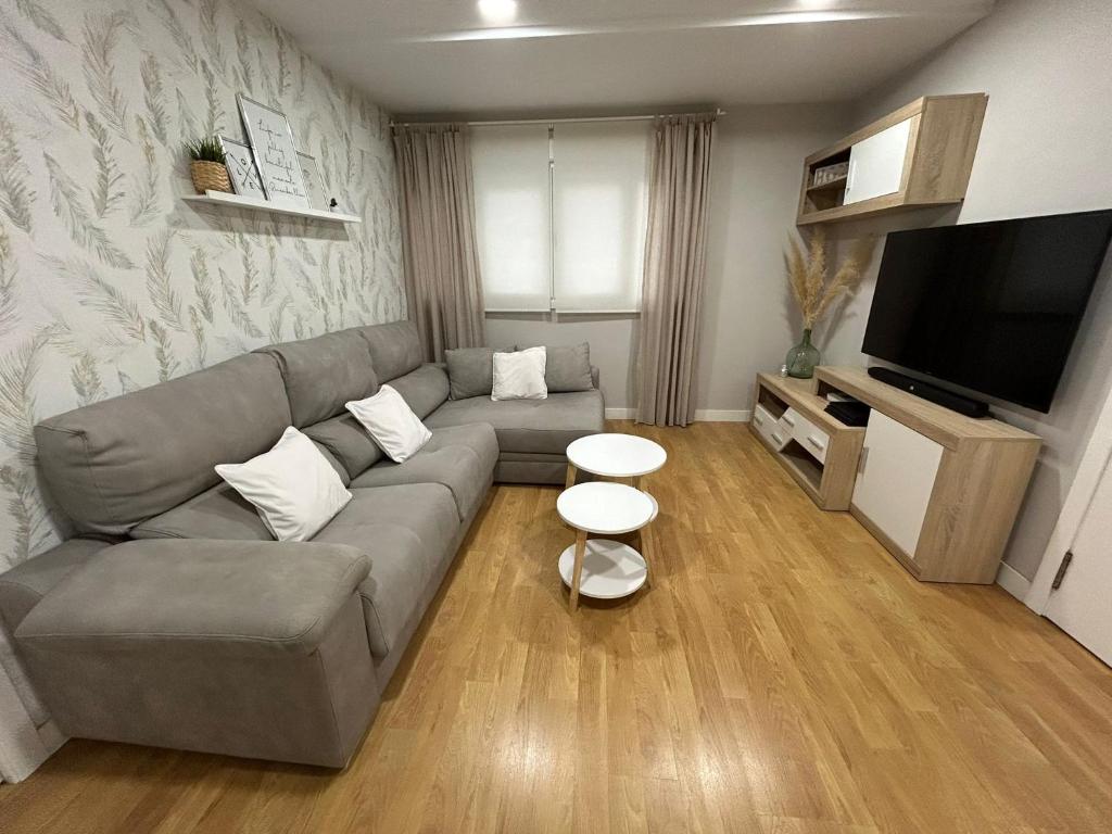een woonkamer met een bank en een flatscreen-tv bij Villa Malena in Chiclana de la Frontera