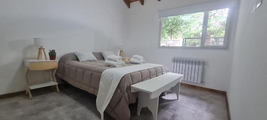 a white bedroom with a bed and a window at Cactus Tempo in Esquel