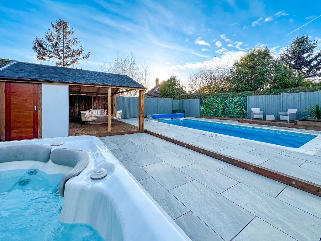 a swimming pool with a hot tub in a yard at Hillside Oasis - Private Hot Tub & Swimming Pool in Fareham