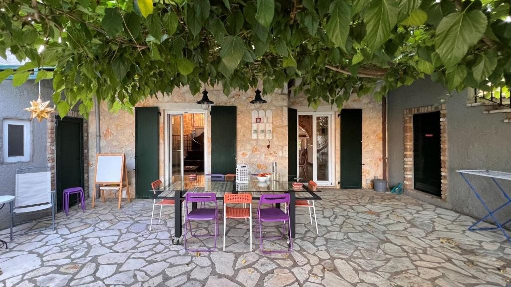 a patio with a glass table and purple chairs at Splendid Gouvia Villa 3 Bedrooms Villa Yiarios Private Playground in Pouládes