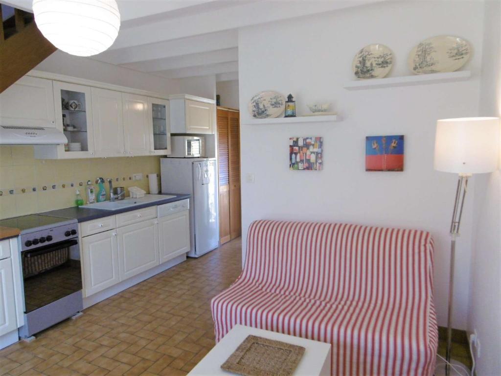 una cocina con armarios blancos y una silla roja y blanca en Maisonnette 3 pièces 4-5 personnes proche de l'océan - WIFI - Lenaig en Sarzeau