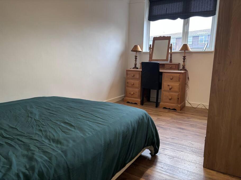a bedroom with a bed and a dresser and a mirror at Cosy Spacious 2 bed flat Hornchurch high street in Hornchurch