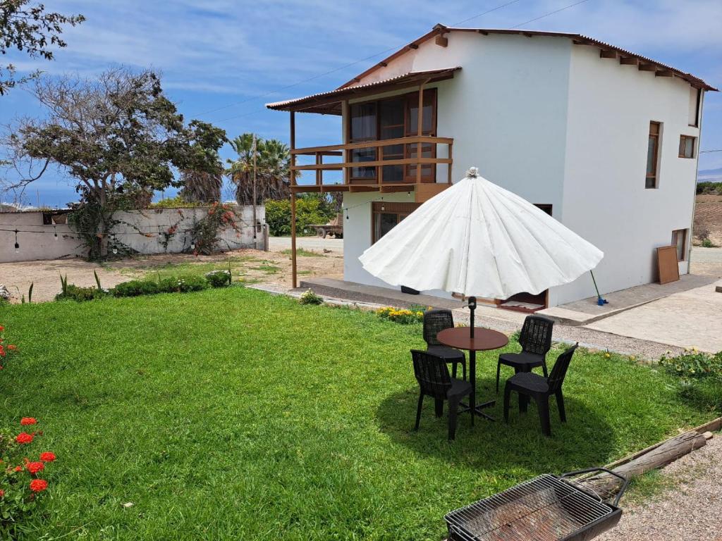 uma mesa e cadeiras com um guarda-sol num quintal em Linda casa de campo en Mejia - Arequipa em Mejia