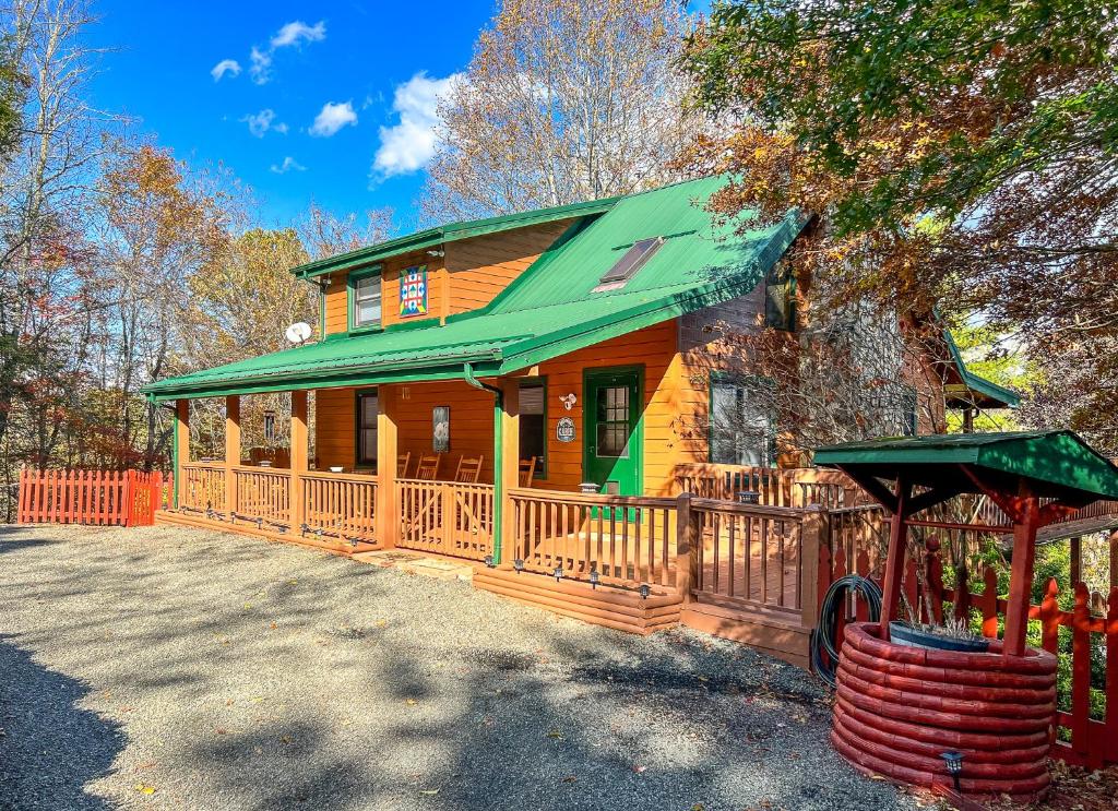 a wooden house with a green roof and a fence at Riverview Ridge in Piney Creek