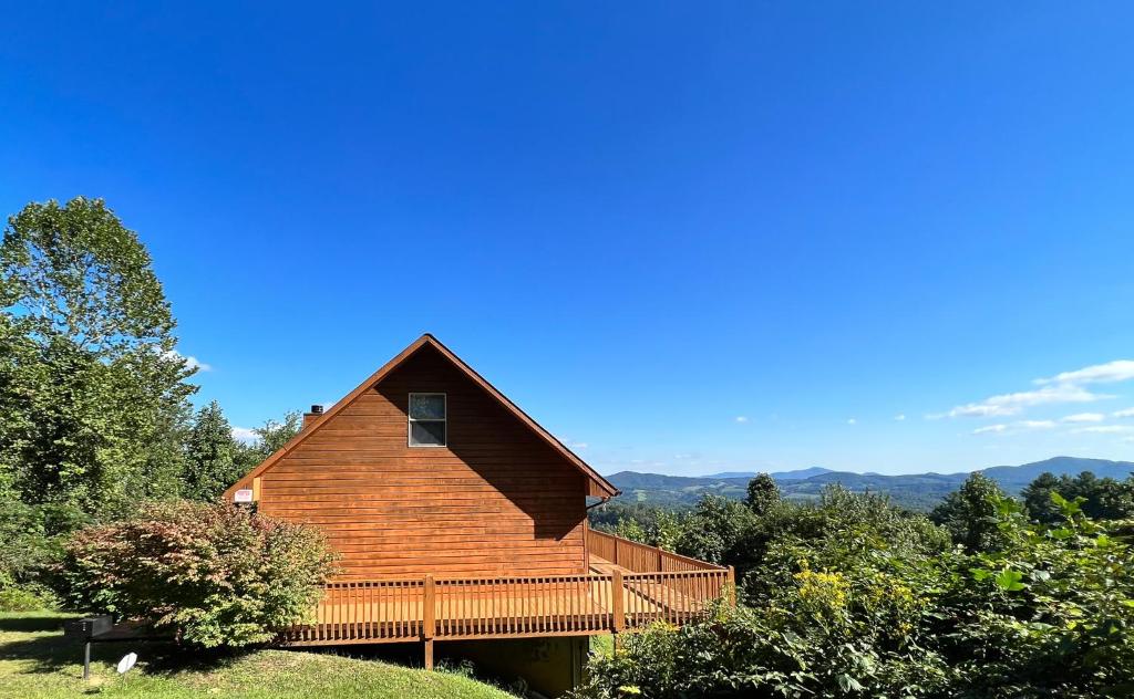 een groot houten huis met een terras op een heuvel bij Above It All in Grassy Creek