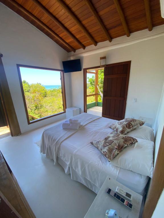 a bedroom with a large bed with a large window at Casa Lua Cheia in Praia do Espelho
