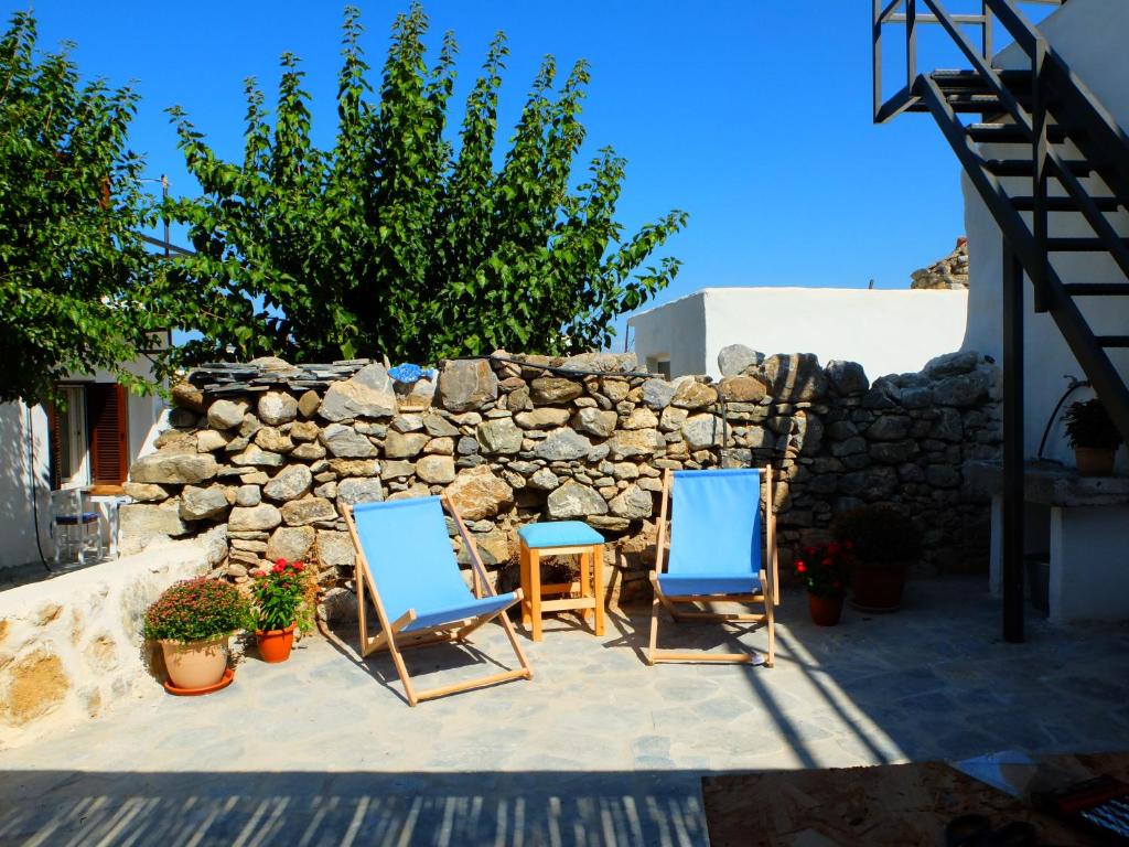two chairs and a table and a stone wall at Kavousi Cottages - O Stavlos in Kavoúsion