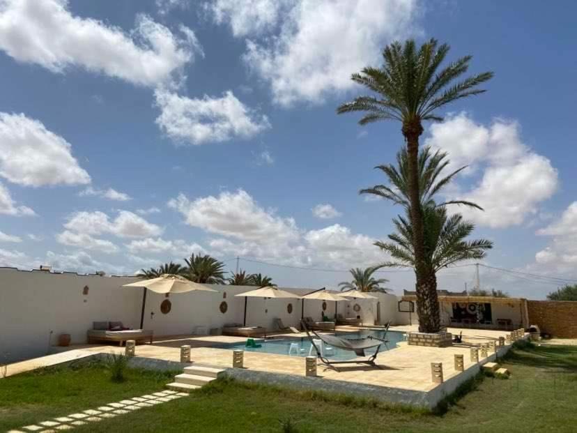 a villa with a palm tree and a swimming pool at Dar Oueghlani - Maison d'hôtes in El Mây