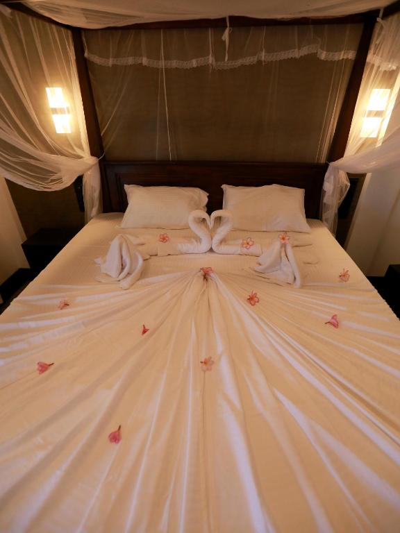a white bed with pink flowers on it at Sea View Villa in Hikkaduwa