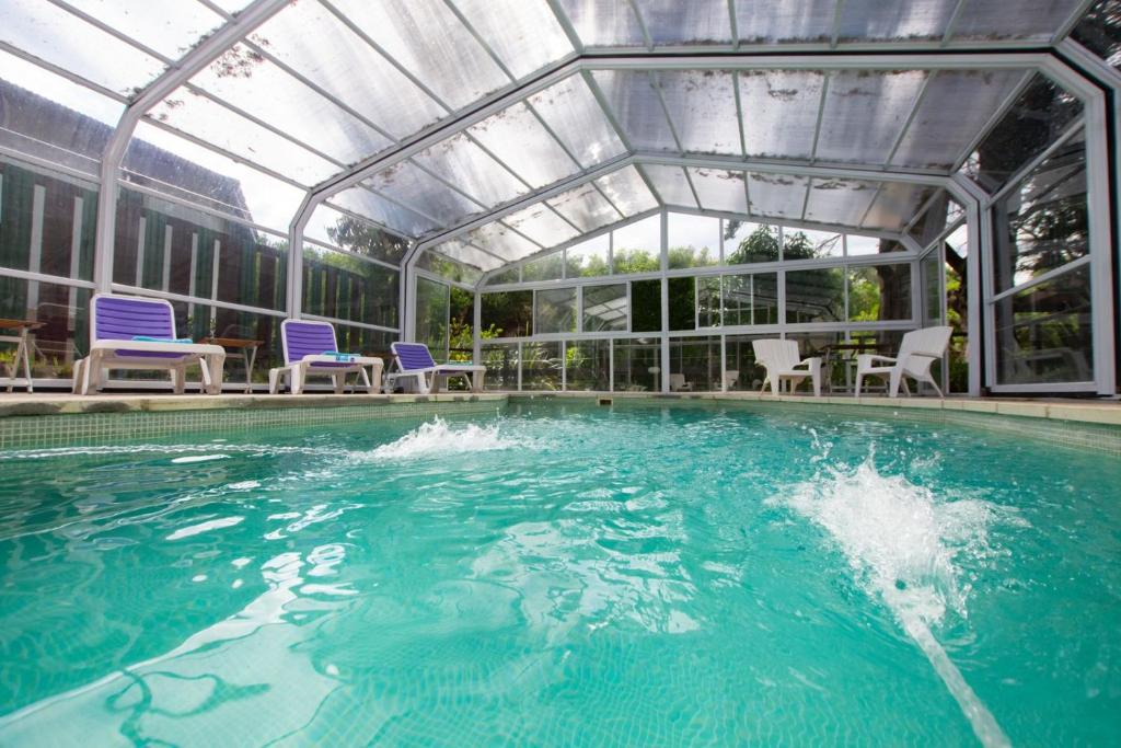 a swimming pool with blue chairs and an indoor poolvisor at E Luru in Mar de las Pampas