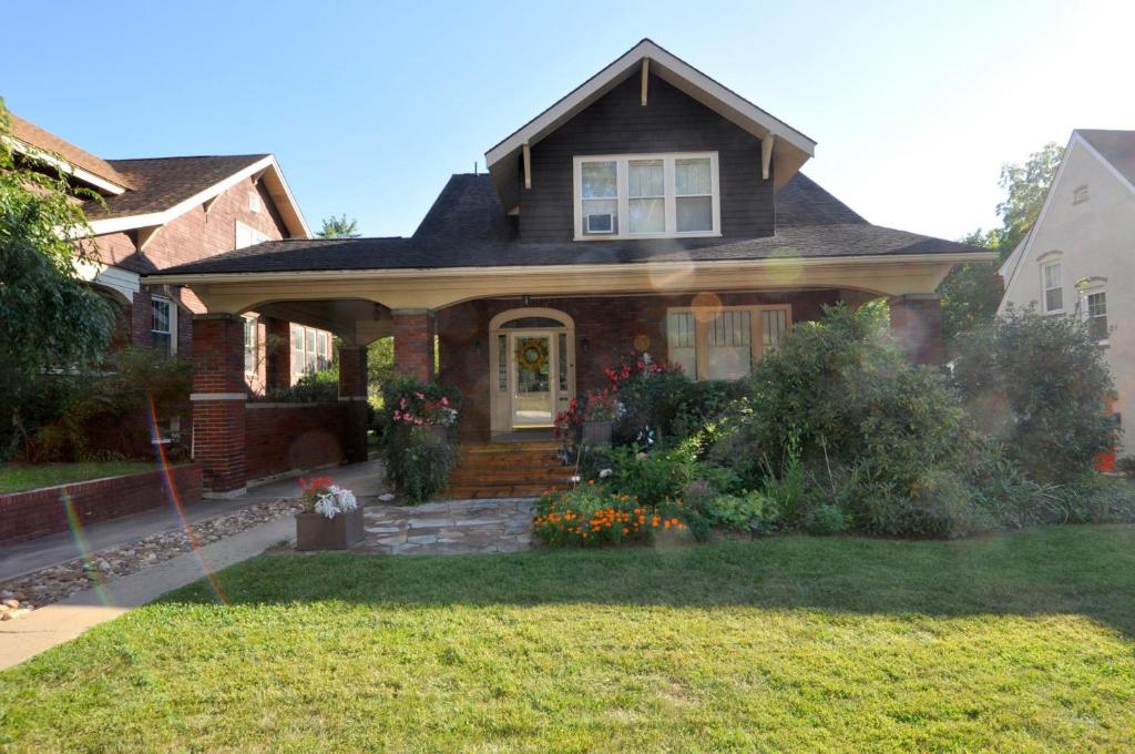 a brown house with flowers on the front yard at Aunt Bea's Bungalow - Pet Friendly - Hot Tub - Screen Porch - Wifi - Fenced Yard - King Bed - Town in Berkeley Springs