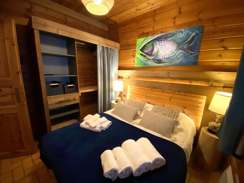 una camera da letto con un letto blu e asciugamani di LE FISHING LODGE Chalet en bois avec bain nordique a La Bresse