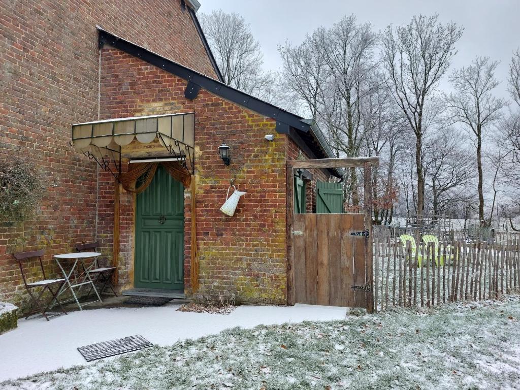 een bakstenen gebouw met een groene deur en een hek bij Le Petit Refuge 