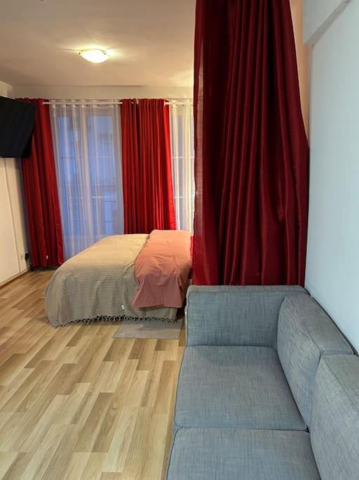 - une chambre avec un lit, des rideaux rouges et un canapé dans l'établissement Appart Paris 10 eme, à Paris