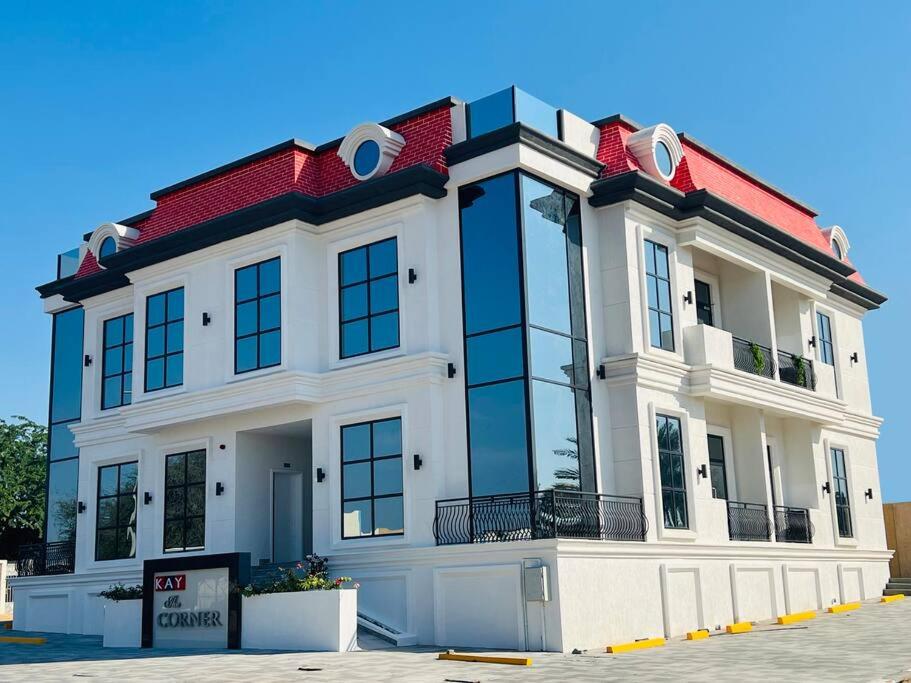 duży biały budynek z czerwonym dachem w obiekcie The Corner, Luxury One-Bedroom w mieście Ras al-Chajma