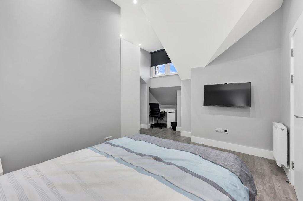 um quarto branco com uma cama e uma televisão de ecrã plano em Your Cosy Stay Modern 2 Double Bedroom Flat Fully Furnished - 5 Mins walk to Stn em Londres