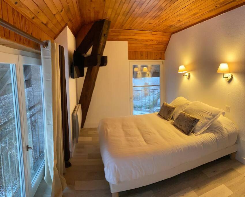 1 dormitorio con cama blanca y techo de madera en Villa sans soucis, en Gérardmer