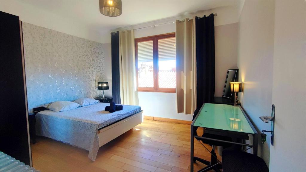 a bedroom with a bed and a desk and a window at Chambre Luxurieux Gris in Perpignan