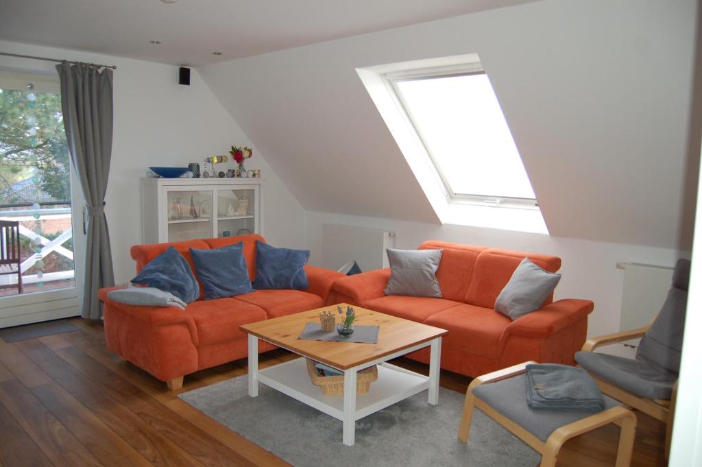 ein Wohnzimmer mit zwei orangenen Sofas und einem Tisch in der Unterkunft Ferienwohnung Oberdeck in Fehmarn