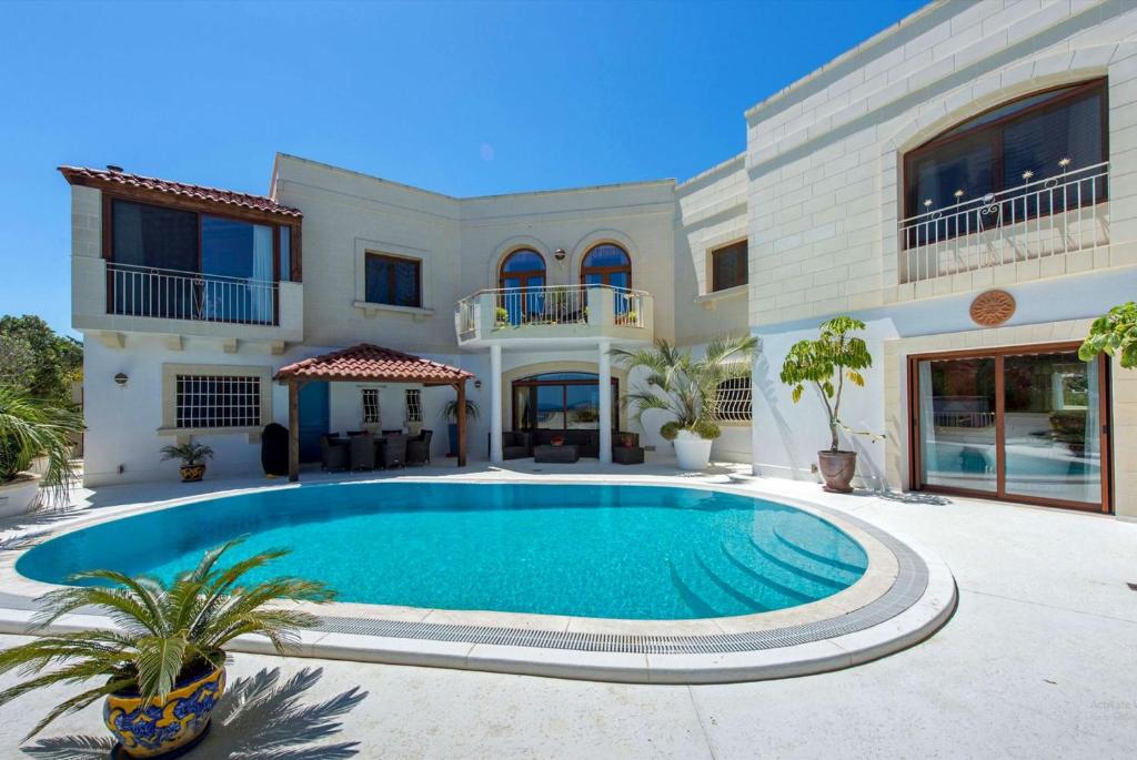 una casa grande con piscina frente a ella en Villa Alexandra - Sunset Sea Views, Heated Jacuzzi, Sauna and Gym, en Mellieħa