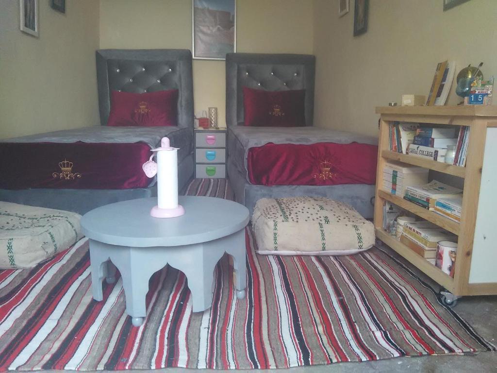 um quarto com 2 camas e uma mesa com uma vela em Grotte de pêcheurs RITAJ, Aglou em Tiznit