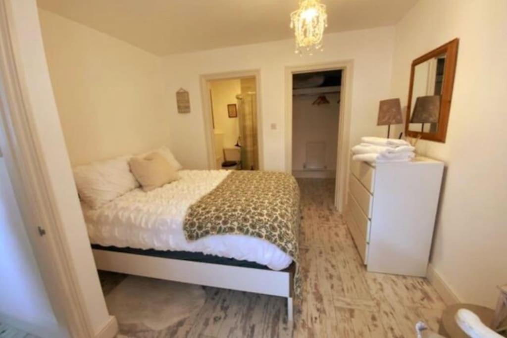 a bedroom with a bed and a dresser and a mirror at Beautiful 1 bed annex, near beach and shops in Iford