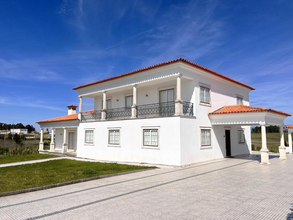 une maison blanche avec un balcon dans une allée. dans l'établissement Casa da Cabeceira Dónica by LovelyStay, à Paredes do Bairro