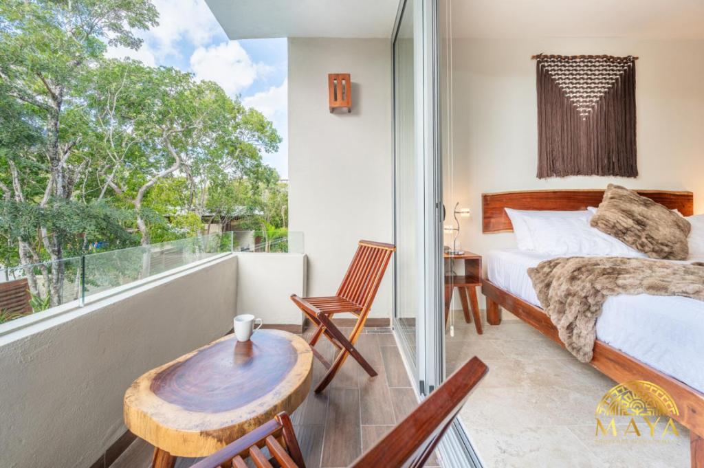 Un dormitorio con una cama y una mesa y una ventana. en NHOA 211B Lux 1BR Condo Pool View in Aldea Zama, en Tulum