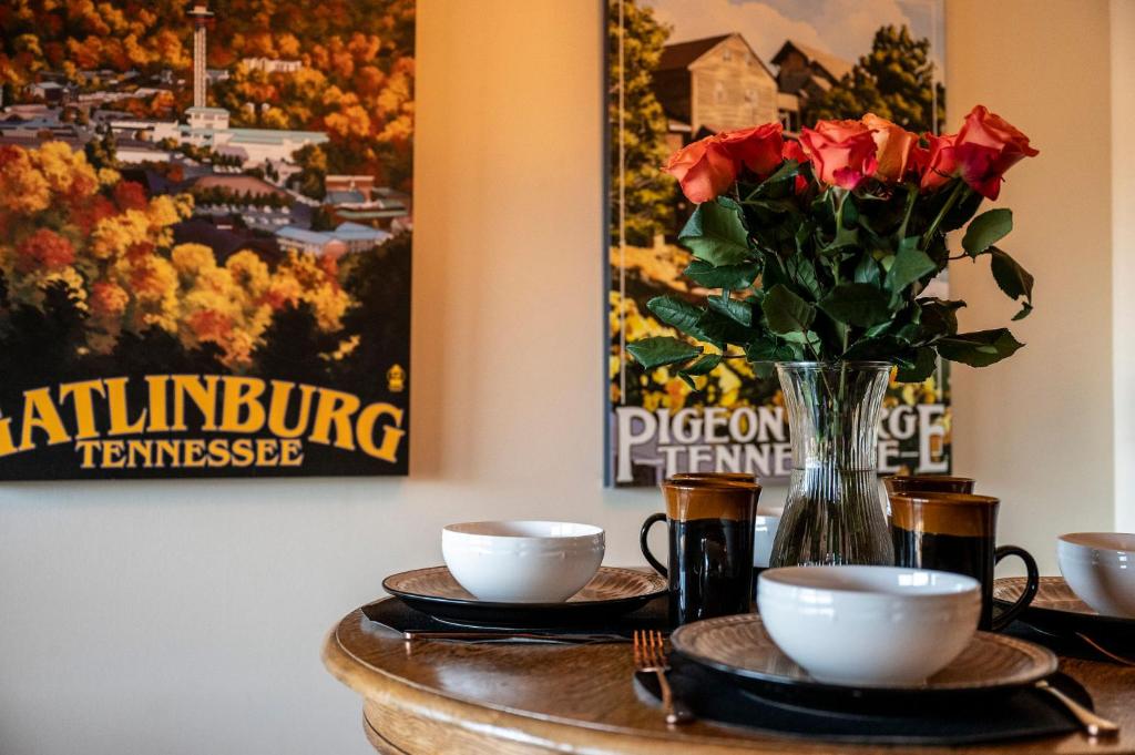 a table with two cups and a vase with roses at Stylish 1BR Free Attraction Tix Views! in Gatlinburg