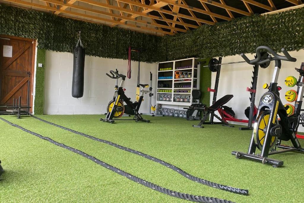 a gym with treadmills and exercise bikes on the floor at The wellbeing XCAPE Country Barn PT & Masseur - H in Nuneaton