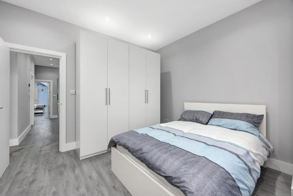 a white bedroom with a bed and white cabinets at Your Cosy Stay Modern 3 Double Bedroom Apartment - Fully Furnished - 5 Mins walk to Stn in London