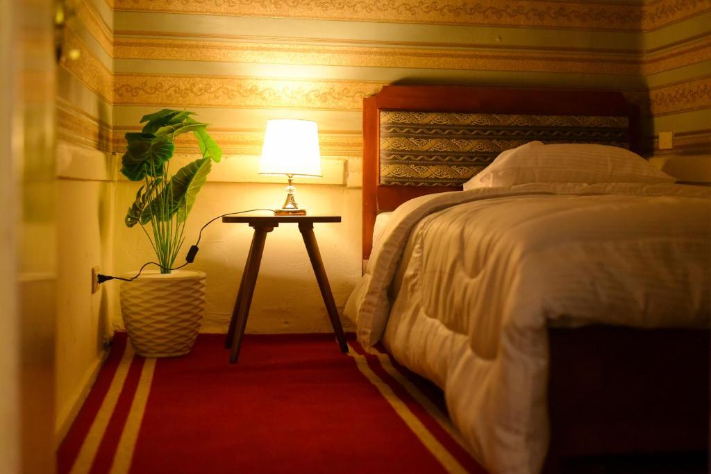 a bedroom with a bed and a table with a lamp at Le Caire Guest Houes Cairo in Cairo