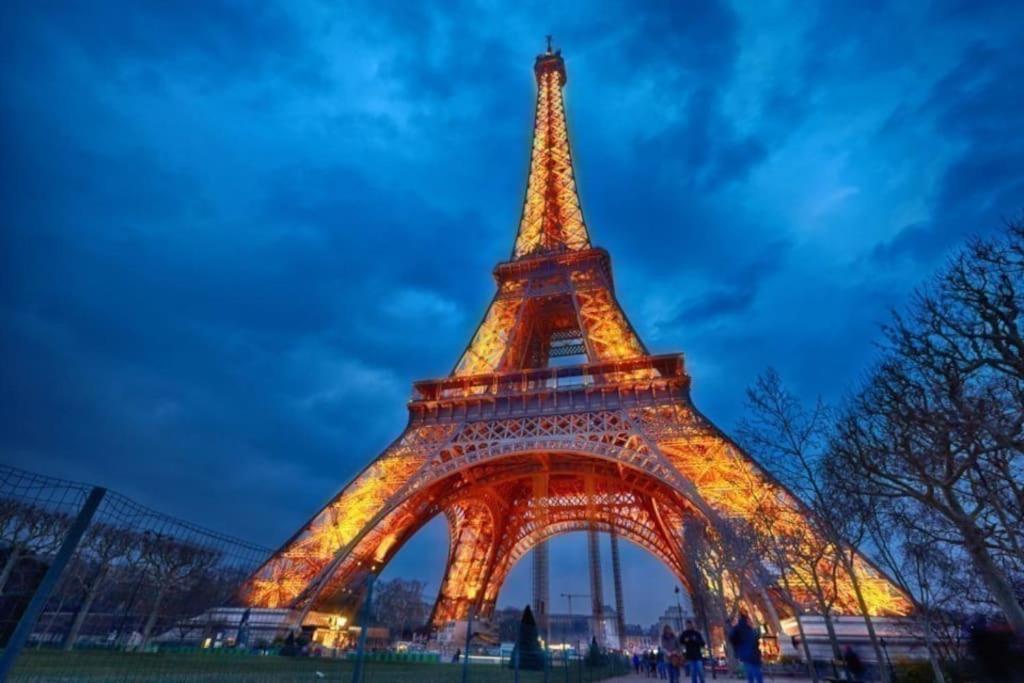 uma vista da torre Eiffel iluminada à noite em House famille Proche 5´ CDG Roissy Aéroport em Gonesse