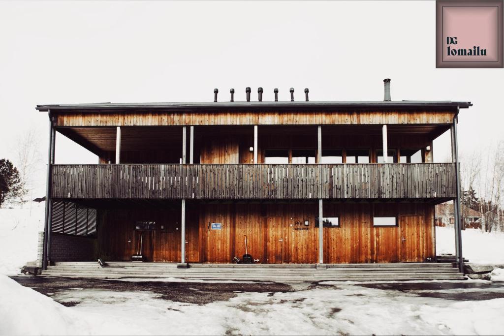 un edificio de madera con nieve en el suelo en Ameno 2, Himos by DG Lomailu, en Jämsä