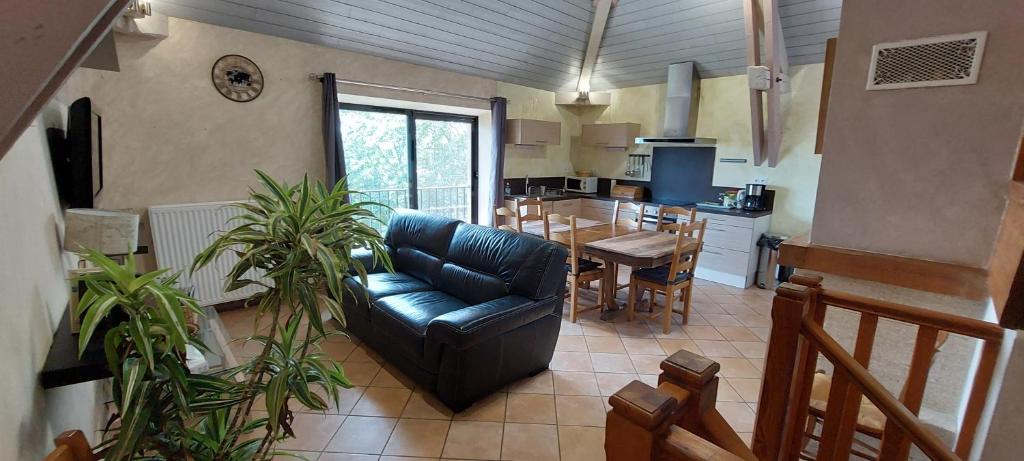 un salon avec un canapé noir et une cuisine dans l'établissement Maison de vacances vue panoramique le Pailler 4 à 9 personnes, à Millau