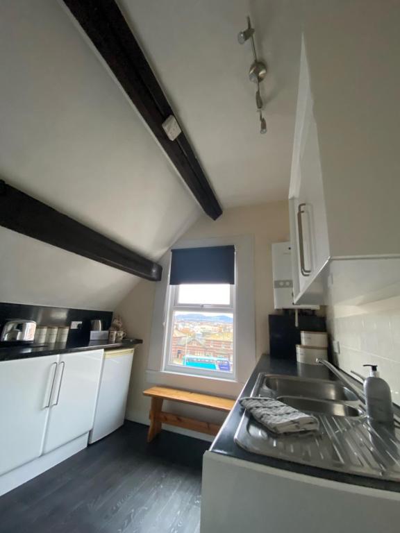 a small kitchen with a sink and a window at Aisha’s Attic in Rhyl