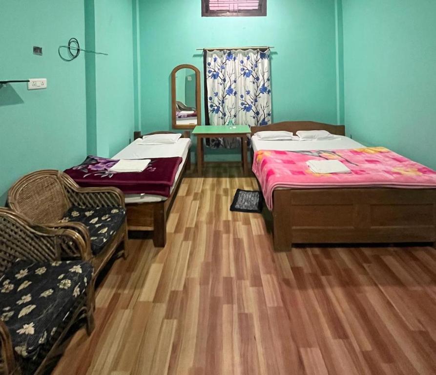 um quarto com duas camas e duas cadeiras e um espelho em Song by meadow homestay em Kaziranga