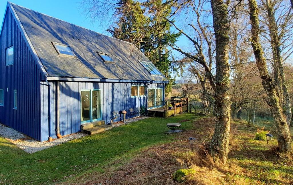 a blue barn with a yard and a tree at Ptarmigan Cottage in Aviemore