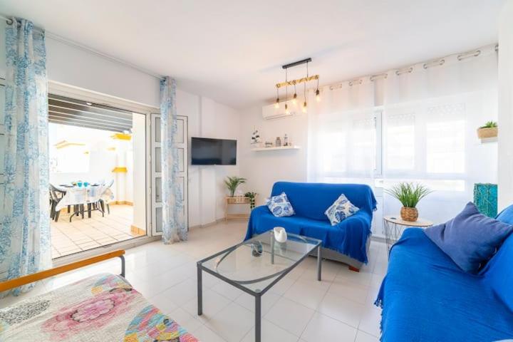 ein Wohnzimmer mit einem blauen Sofa und einem Tisch in der Unterkunft Apartº Roquetas de Mar 1º linea playa in Roquetas de Mar