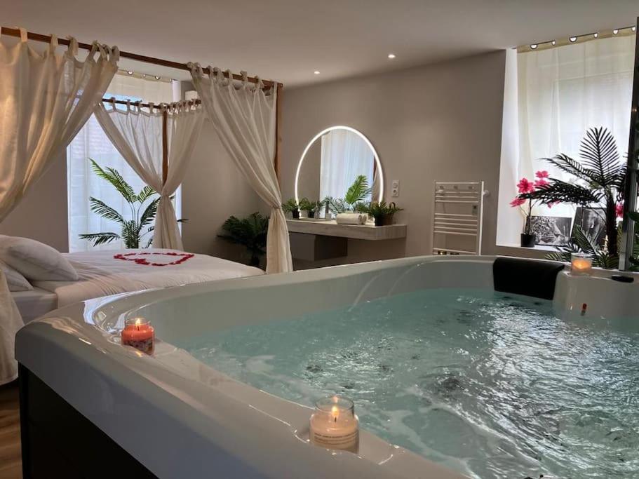 - une grande baignoire dans une chambre avec un lit dans l'établissement Jungle Secret SPA Nuit insolite, à Giromagny