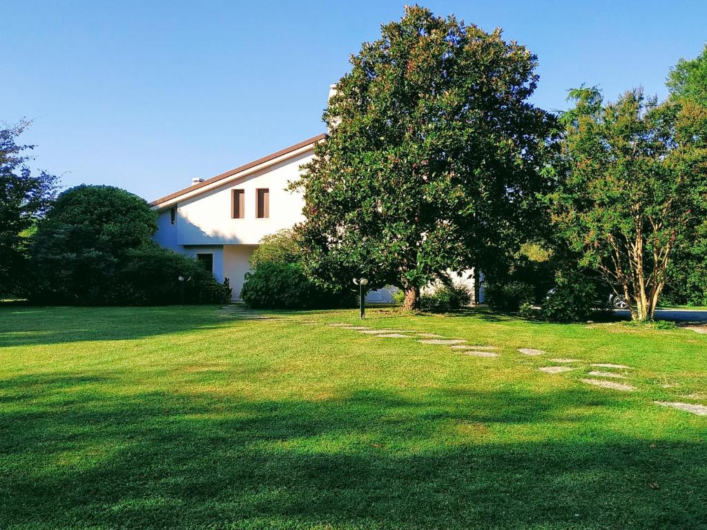 una casa con un gran patio con árboles delante de ella en B&B Villa Elisa, en Motta di Livenza
