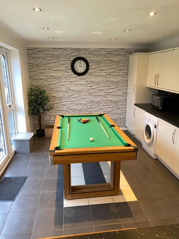 a living room with a pool table and a clock at Lovely family home, 5 minutes from the beach in Clacton-on-Sea