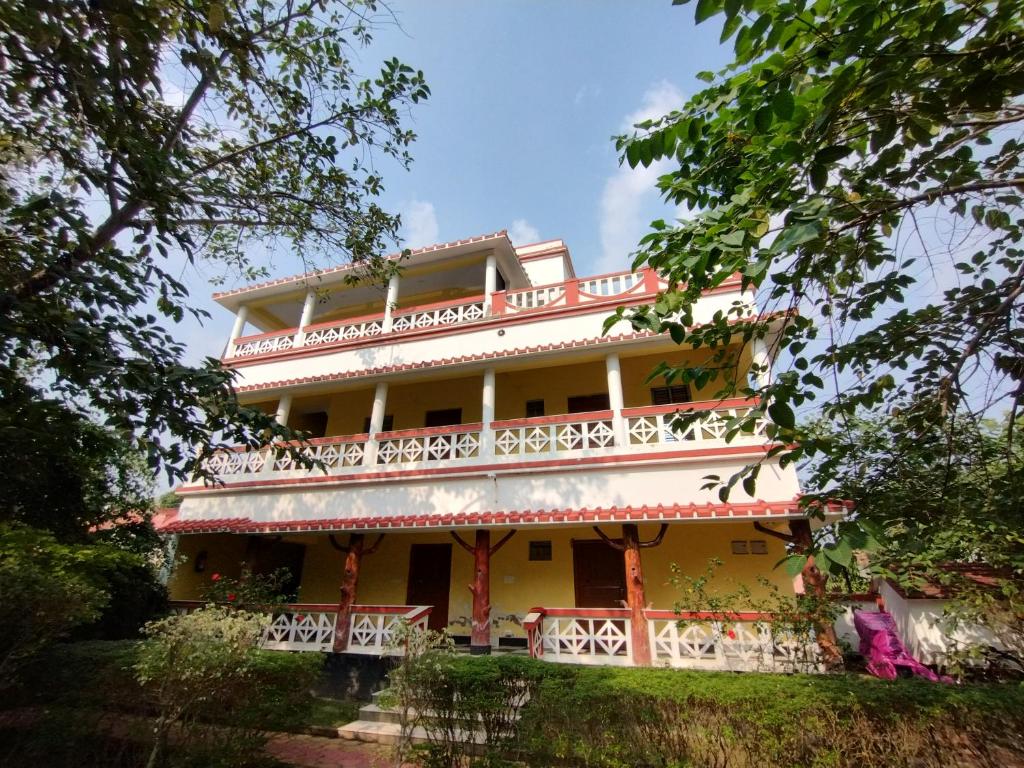 a large yellow building with a balcony at Muktomon Hotel & Resort in Bolpur